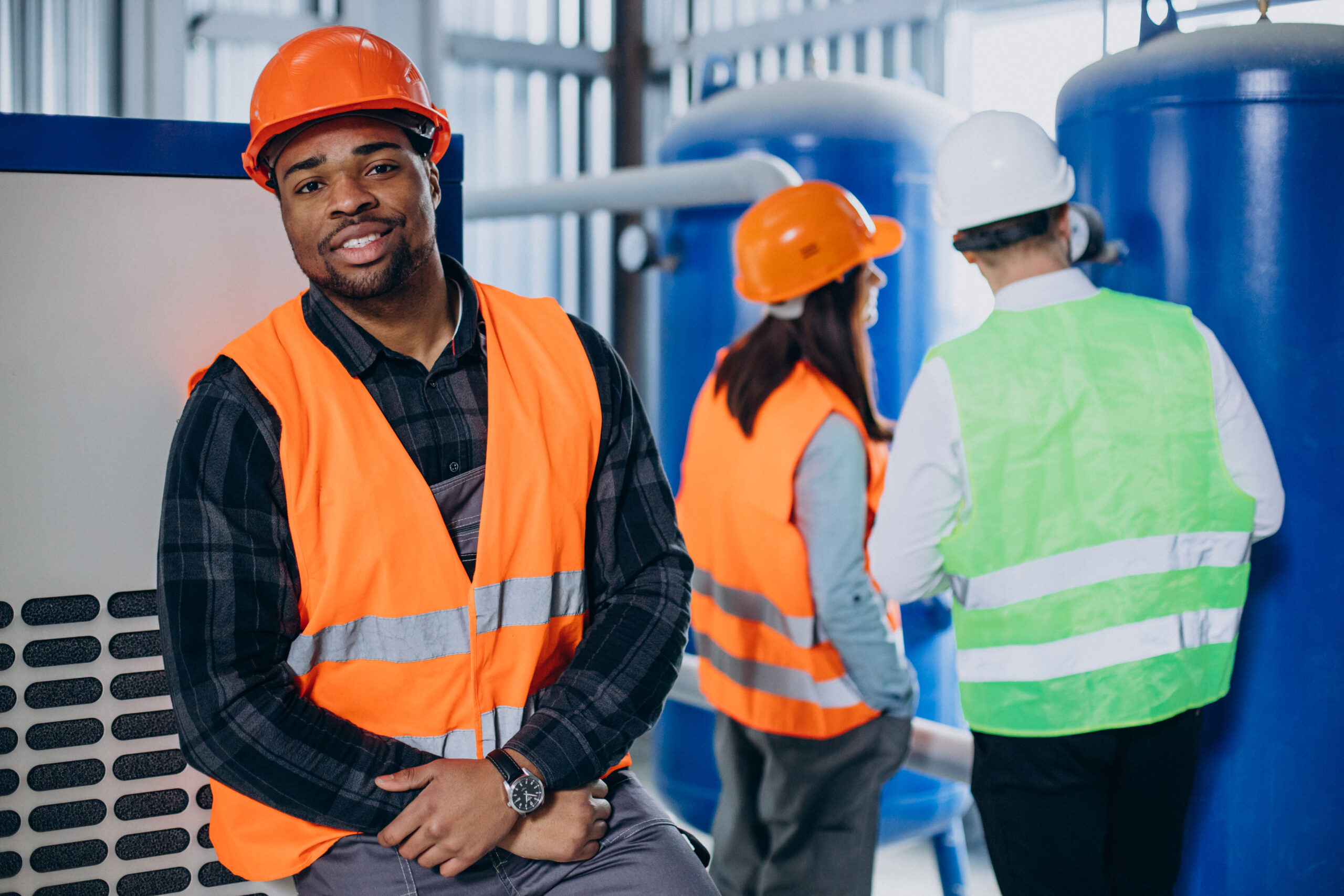three factory workers in safety hats discussing manufacture plan